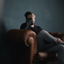 Mann sitzt auf einem Sofa und ist traurig