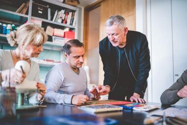 Kreativtherapie - psychotherapeutische Behandlungsform 2 Therapeut erklärt Patient etwas bei der Kunsttherapie