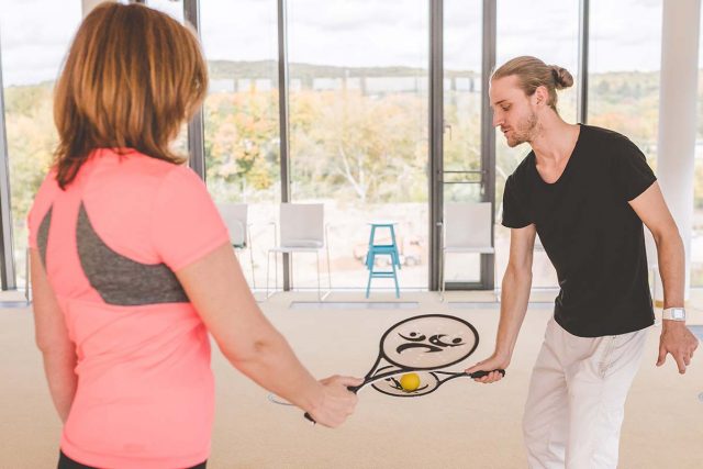 Bewegungstherapien-BetaGenese-Klinik Therapeut erklärt Patientin eine Übung in der Bewegungstherapie