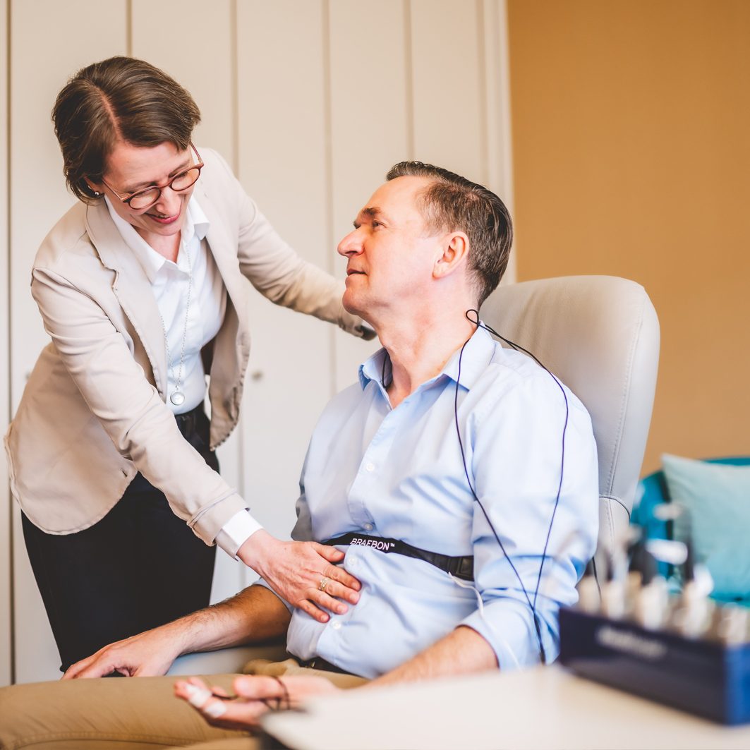 Frau hilft Mann dabei, seine Atmung bei der Neurofeedback-Therapie zu kontrollieren