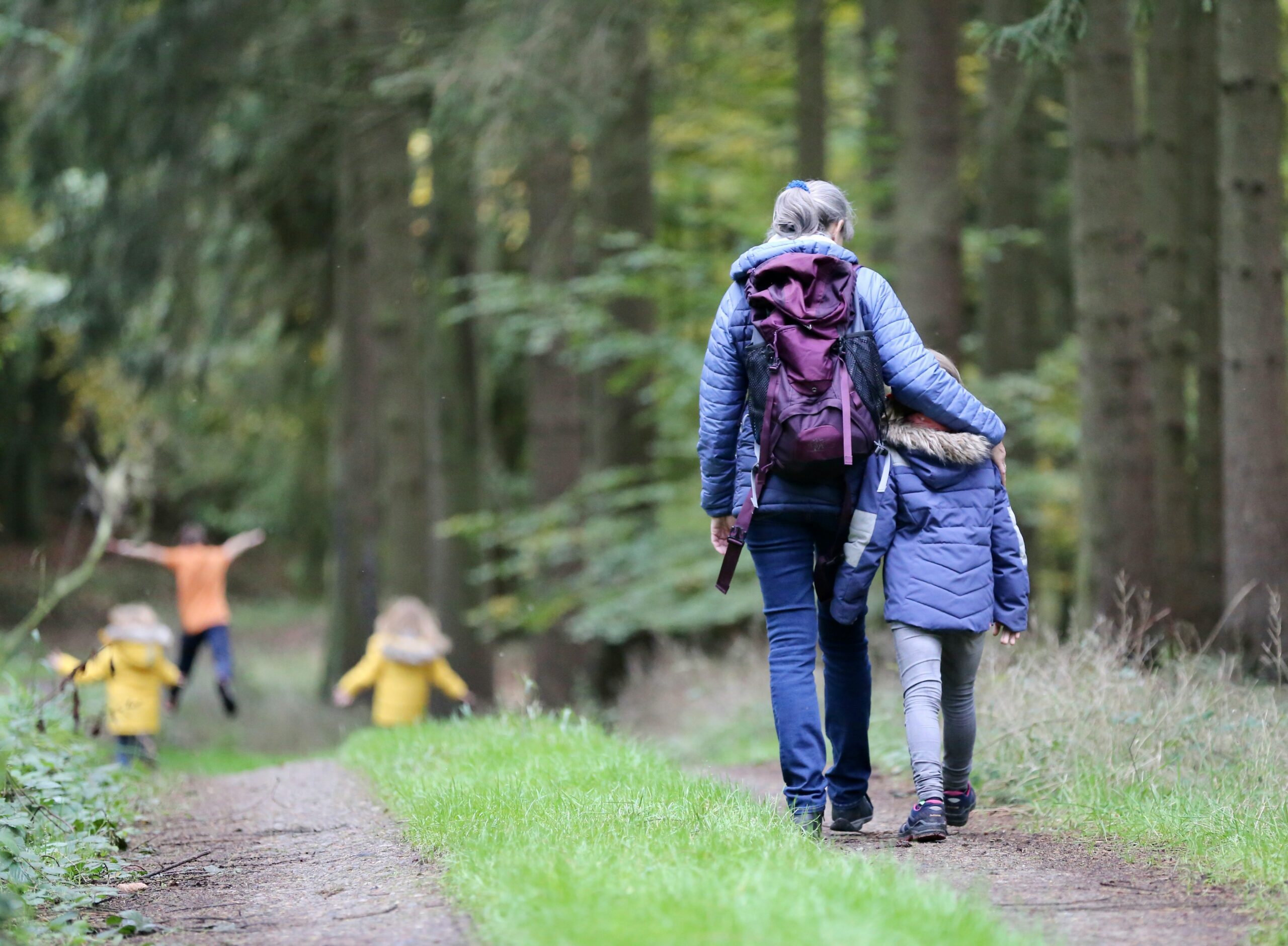 Eine Mutter geht mit ihren Kindern im Wald spazieren.