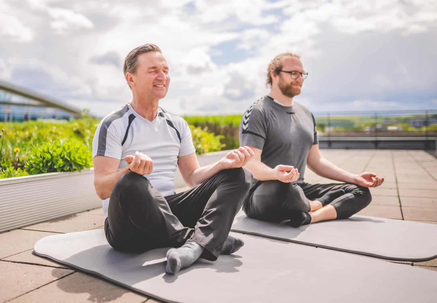 Zwei Personen in Sportkleidung praktizieren Yoga für Entspannung und Körpertherapie