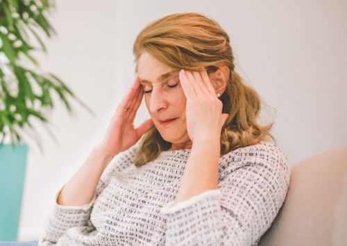Frau reibt sich mit beiden Händen die Schläfen