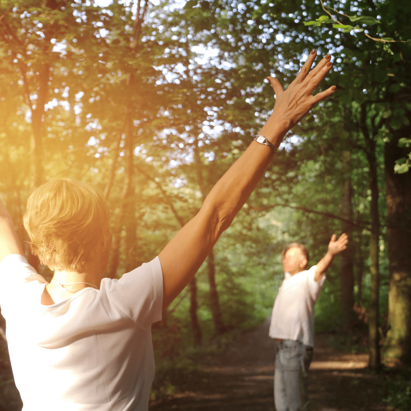 Hyperarousal: Symptome, Ursachen und Behandlung 4 Zwei Personen in einem Wald strecken ihre Arme zum Himmel hinauf