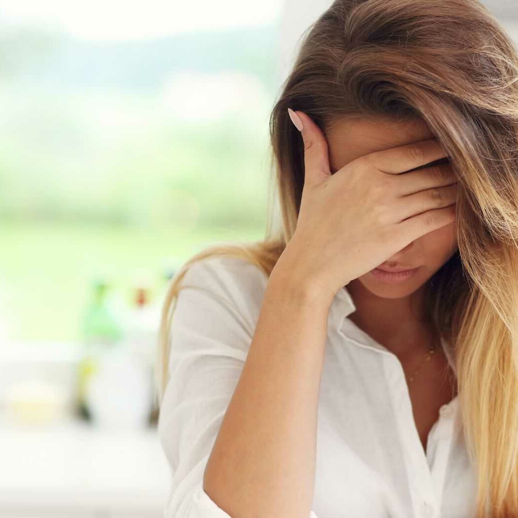 Migräne behandeln Eine Frau fasst sich an den Kopf, weil sie Schmerzen hat