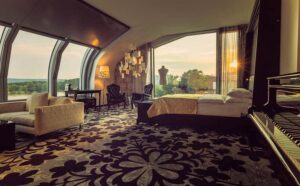 Hotelzimmer im Kameha Grand mit großzügigem Bett, Fensterfront mit Rheinblick und einem Klavierflügel.