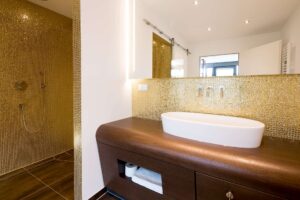 Helles Badezimmer mit goldenen Akzenten und großem Waschbecken.