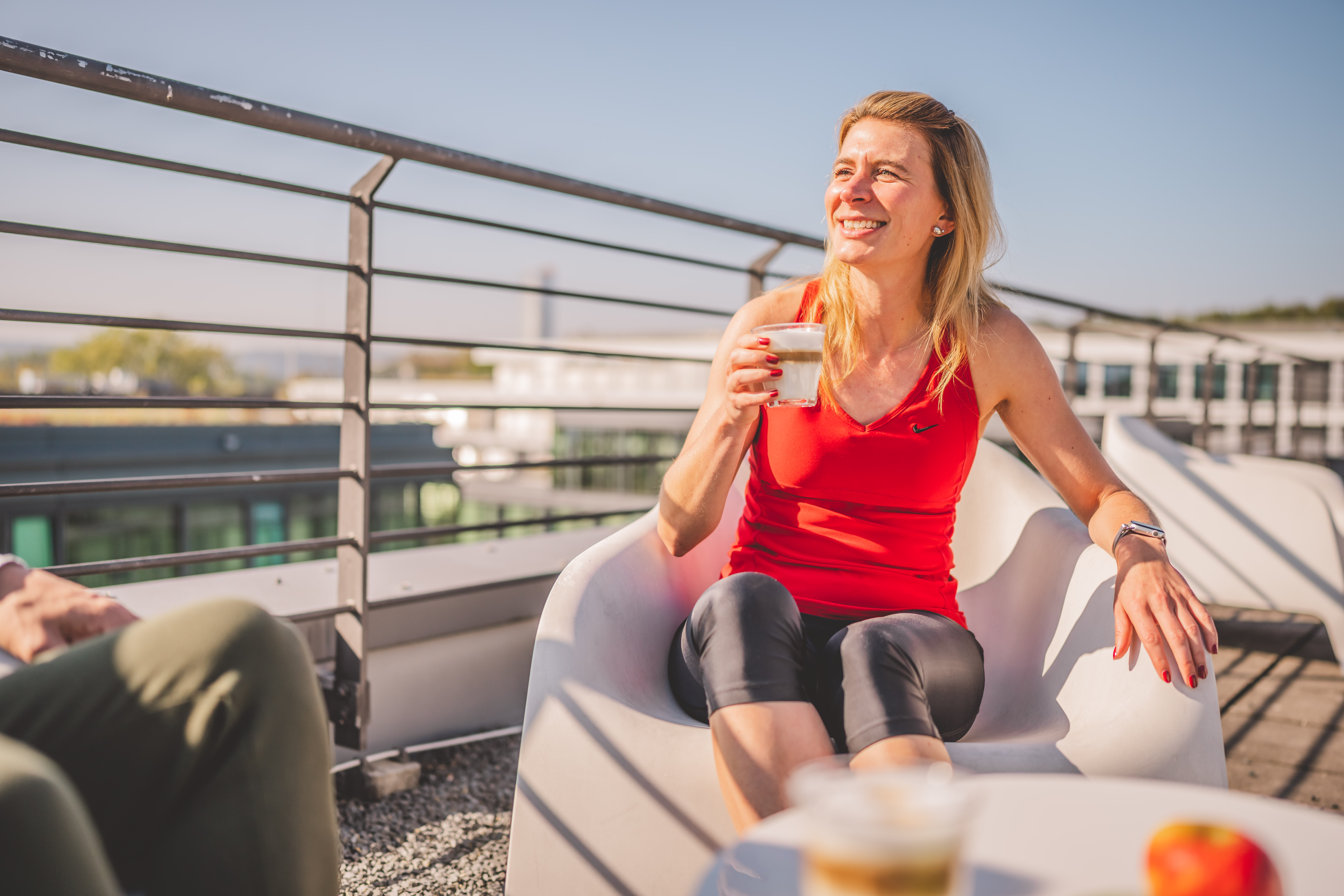 Nahaufnahme einer weiblichen fröhlichen Patientin mit einem Kaffee auf der Dachterasse.