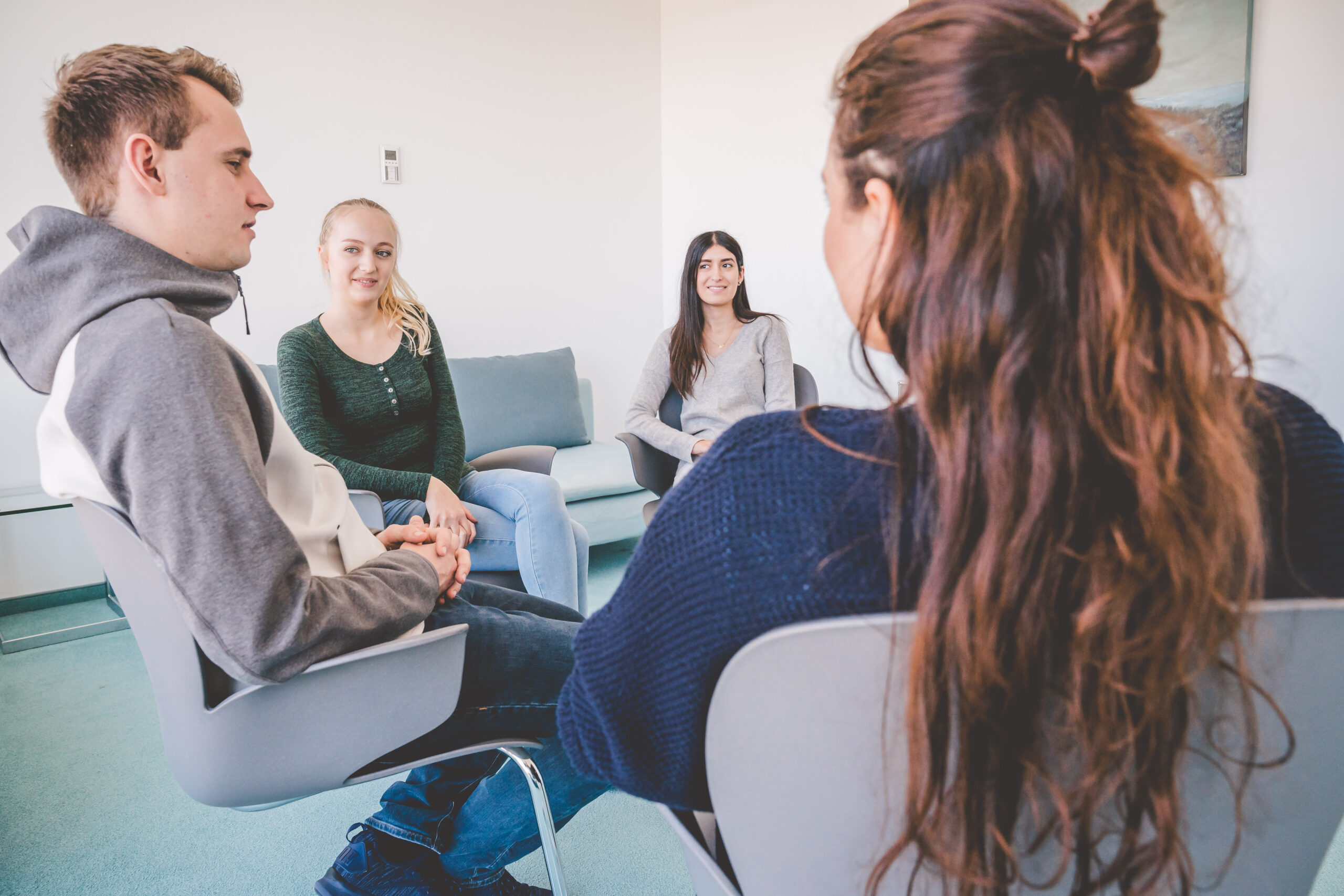 Jugendliche sitzen gemeinsam im Stuhlkreis während der Gruppentherapie.