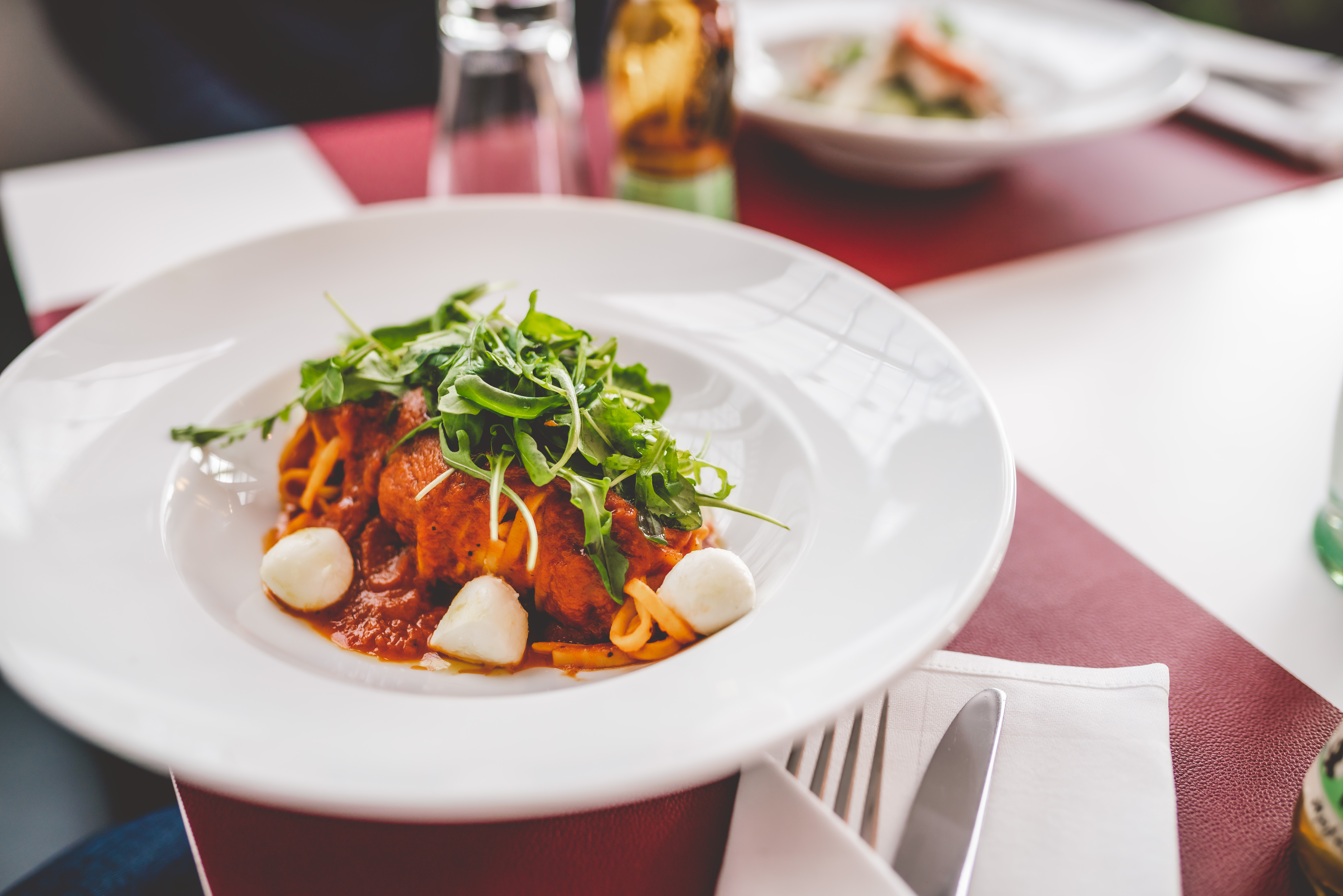 Frisch zubereitetes Gericht mit Gemüse und Rucola auf einem gedeckten Tisch“