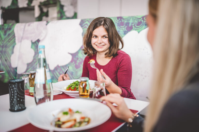 Jugendliche sitzt am Essentisch und genießt das Essen.