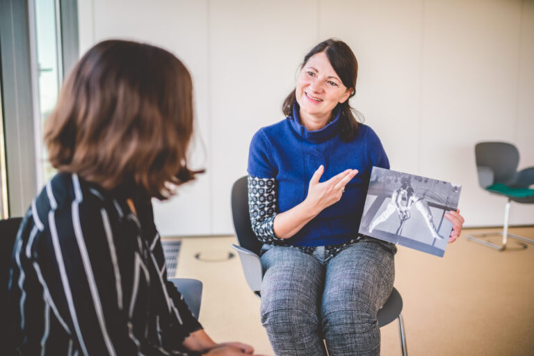 Therapeutin Bettina Post zeigt einer Patientin ein Bild in Folge der Gruppentherapie.