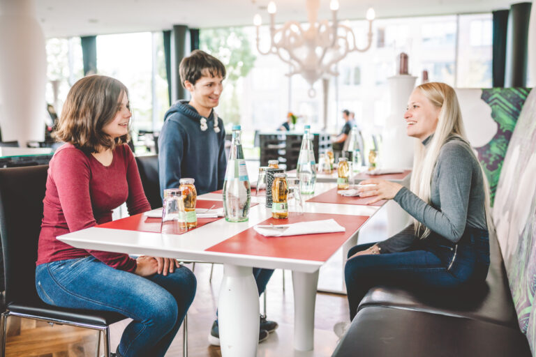 Jugendliche sitzen zusammen am Tisch im Kameha.