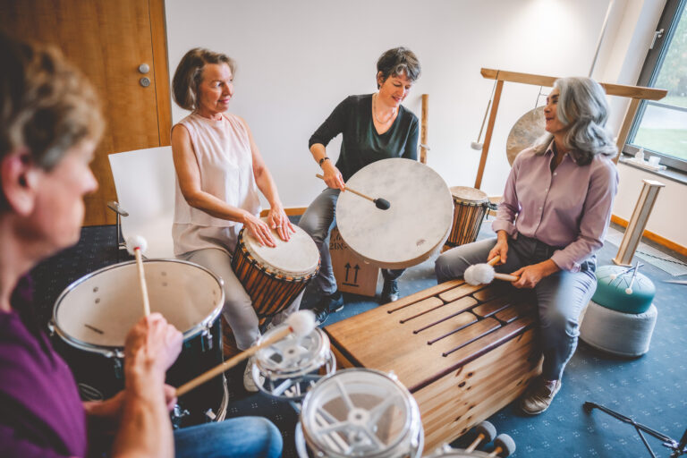 Gruppenfoto der Musiktherapie. Patienten sitzen im Trommelkreis.