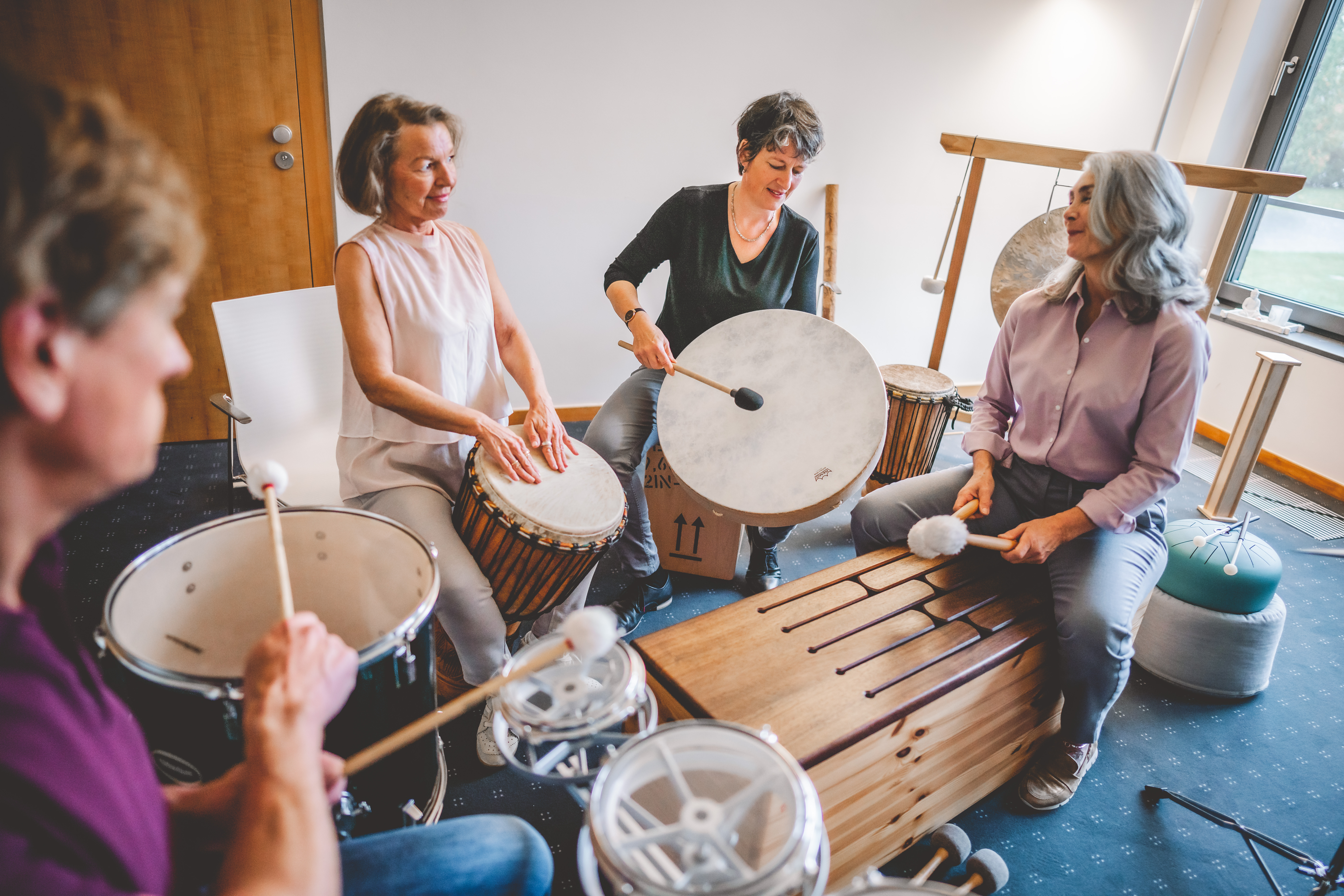 Gruppenfoto der Musiktherapie. Patienten sitzen im Trommelkreis.