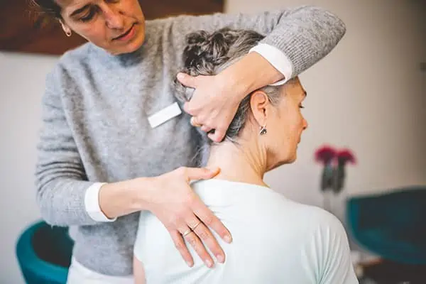 Physiotherapie Behandlung am Nacken einer älteren Patientin.