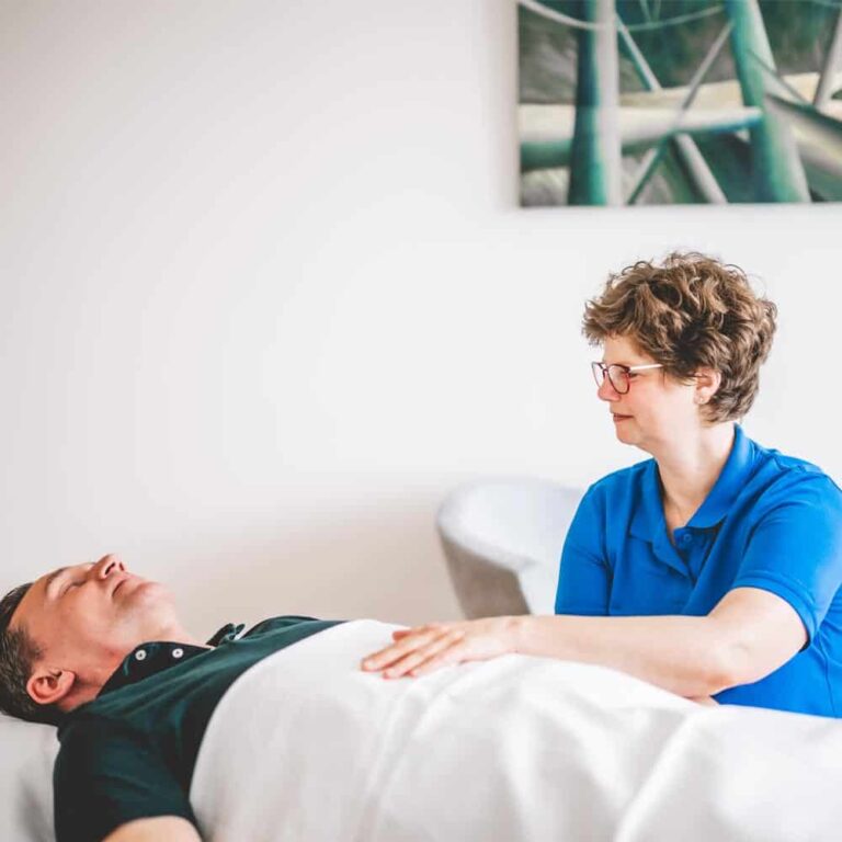 Therapeutin behandelt und spricht mit liegenden Patienten mit chronischen Schmerzen.