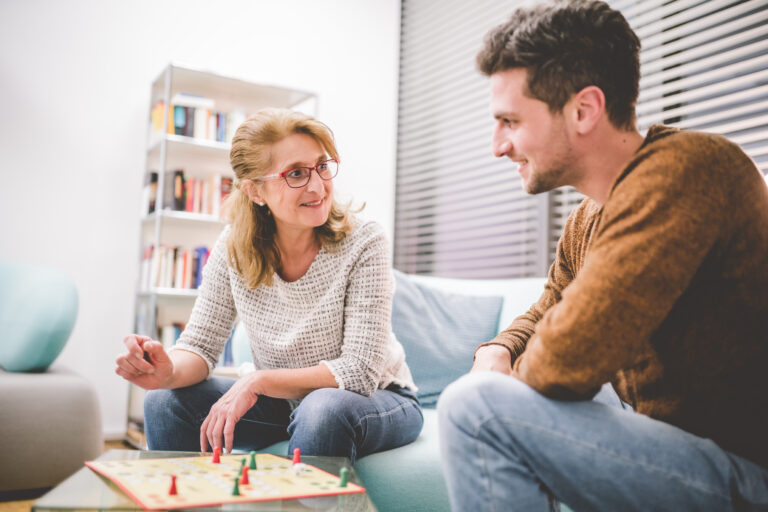 Zwei Patienten sitzen gemeinsam im Aufenthaltsraum und spielen ein Brettspiel miteinander.
