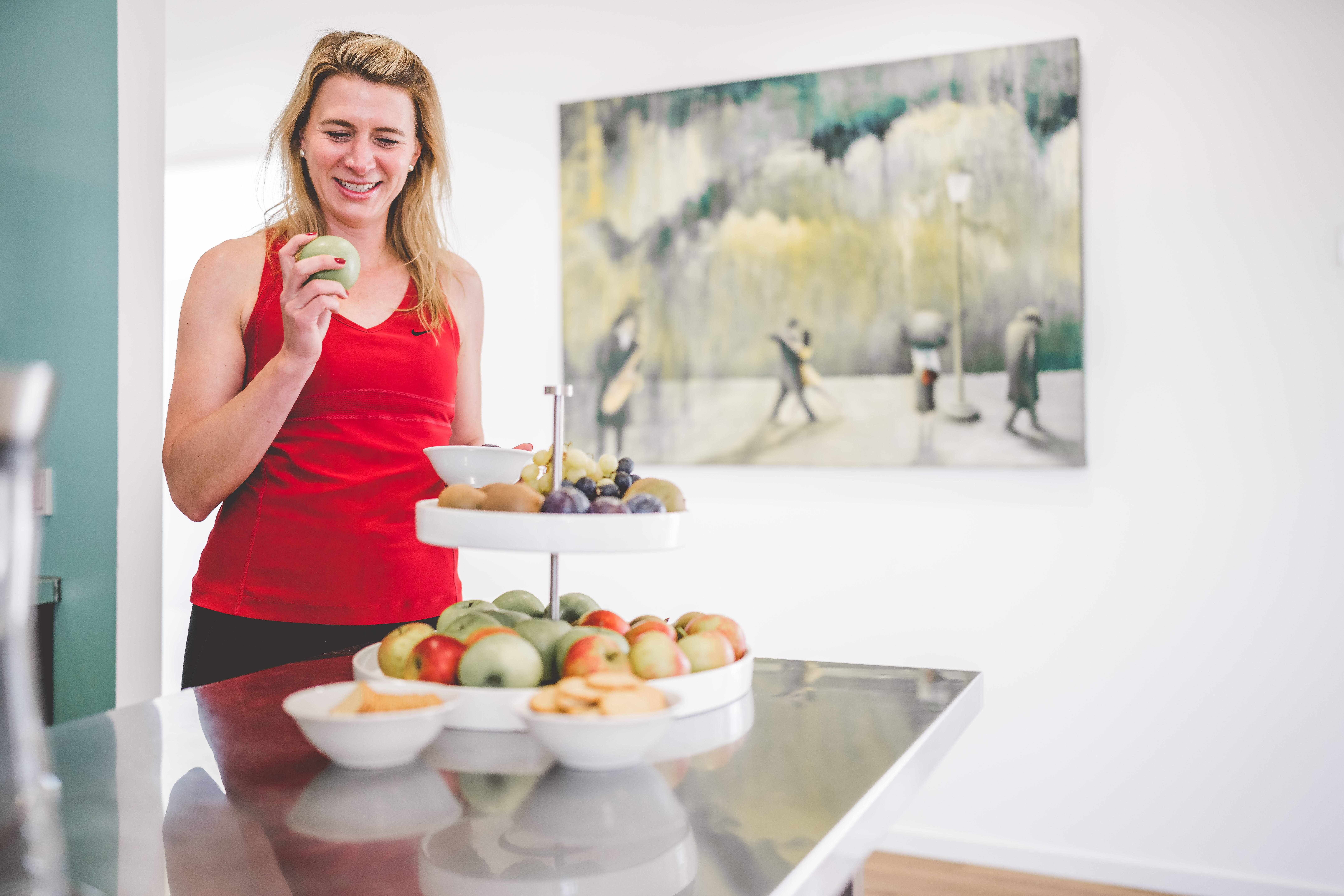 Patientin steht vor einer Obst Etagere und sucht sich lächelnd was aus.